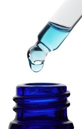 Photo of Dripping light blue facial serum from pipette into glass bottle on white background, closeup