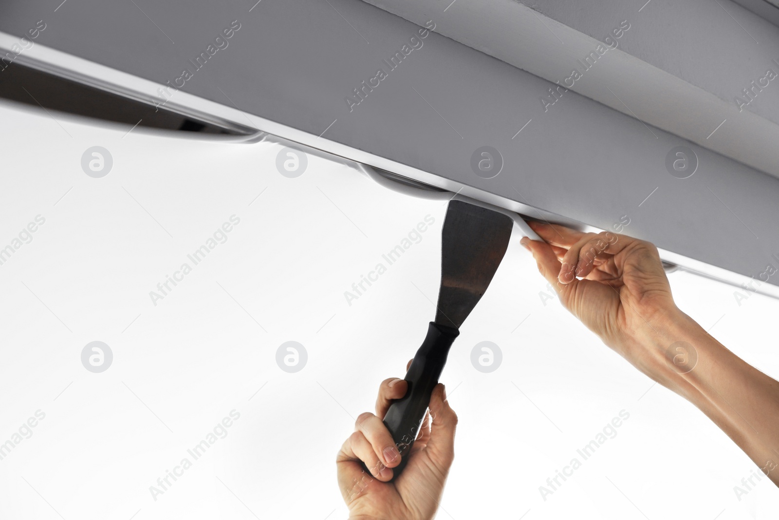 Photo of Repairman installing white stretch ceiling in room, closeup