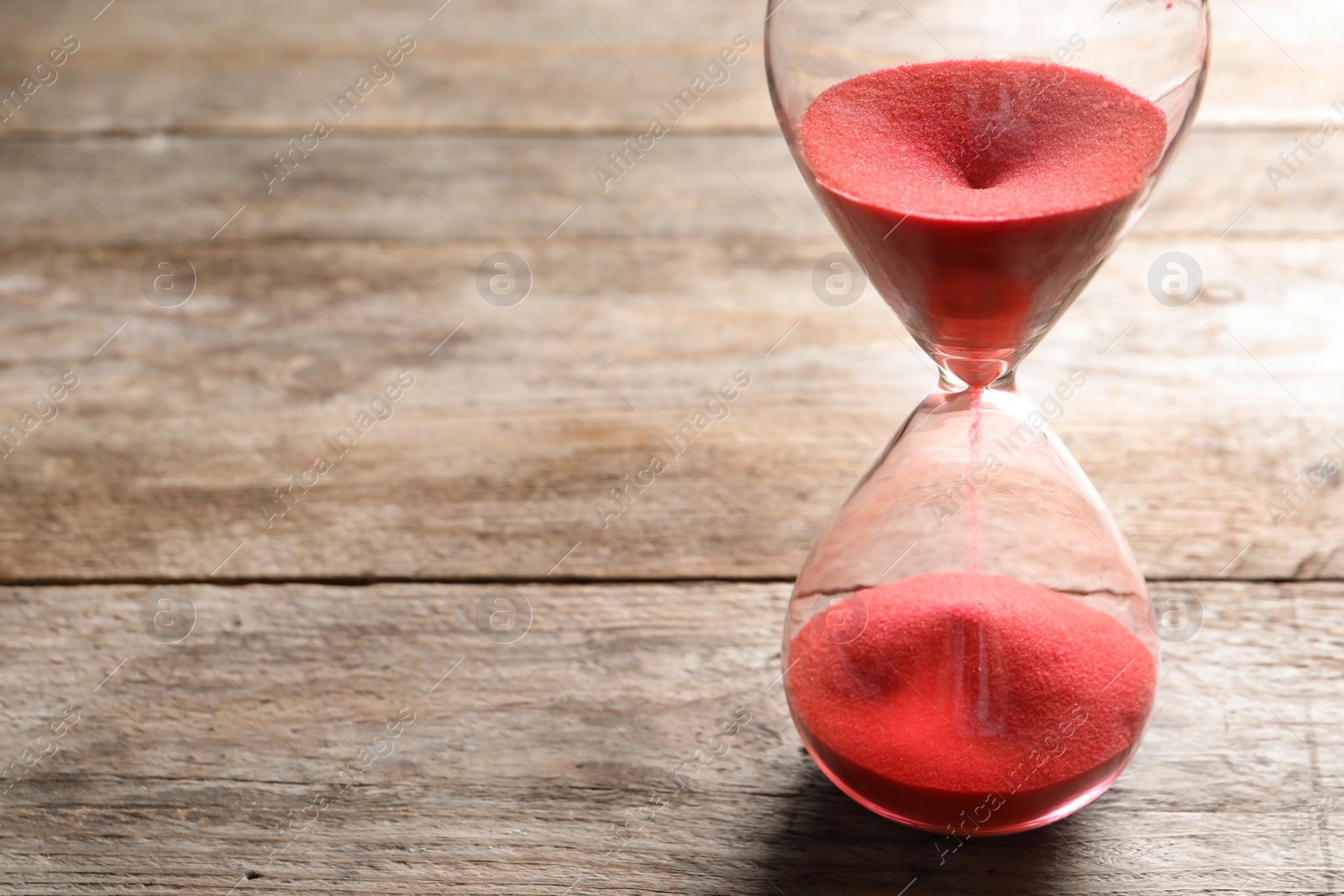 Photo of Hourglass with flowing sand on table. Time management