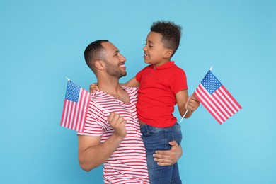 Photo of 4th of July - Independence Day of USA. Happy man and his son with American flags on light blue background