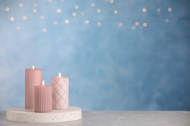 Photo of Burning candles on light grey marble table. space for text