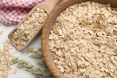 Oatmeal and branches with florets on white table, flat lay