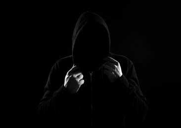 Anonymous man in hood on black background