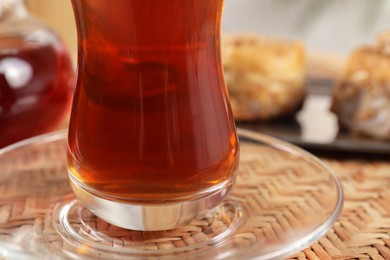 Photo of Traditional Turkish tea in glass on wicker table, closeup