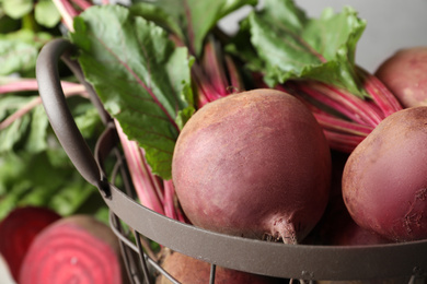 Photo of Fresh red beets with leaves in basket, closeup