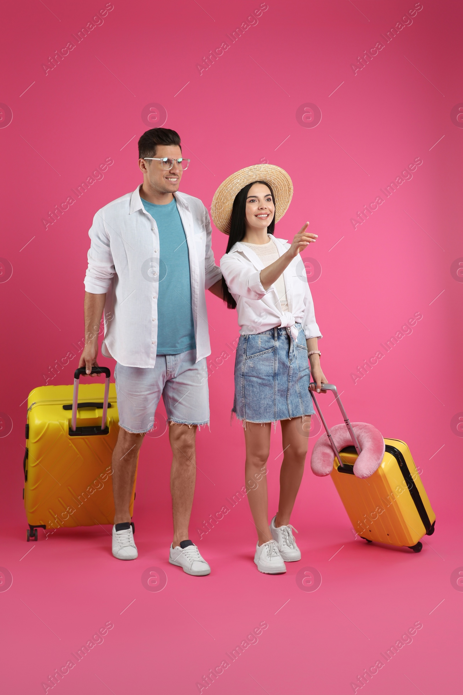 Photo of Couple of tourists with suitcases on pink background