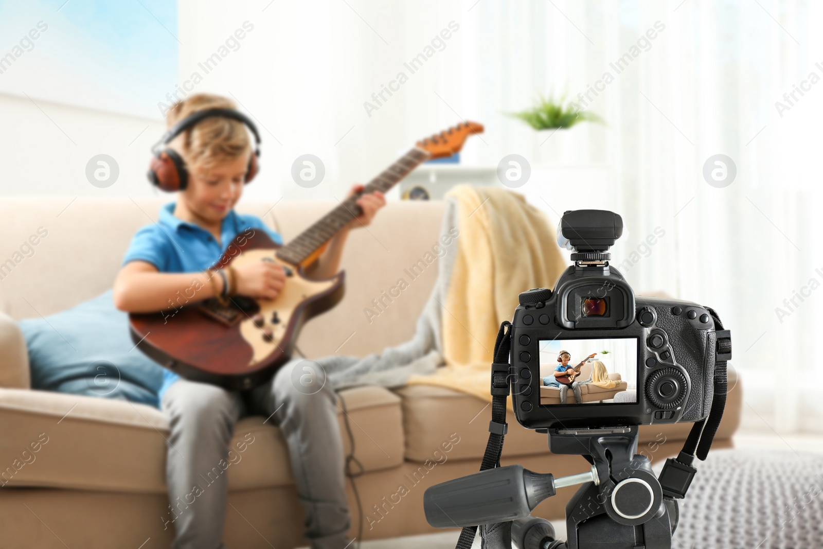 Image of Little music teacher recording guitar lesson indoors