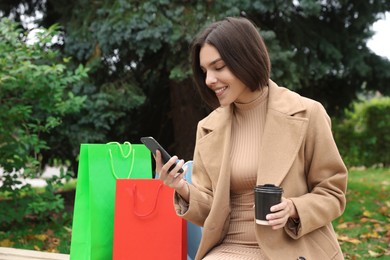 Special Promotion. Happy young woman with smartphone and cup of drink in park