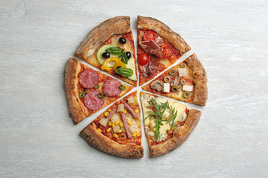 Photo of Slices of different delicious pizzas on light grey table, flat lay