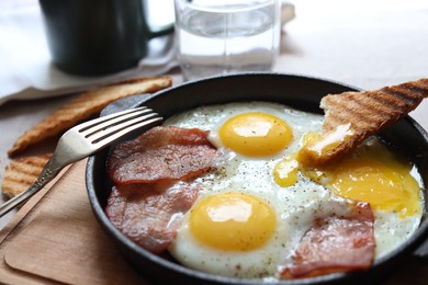 Photo of Tasty fried eggs with bacon and toast on table, closeup