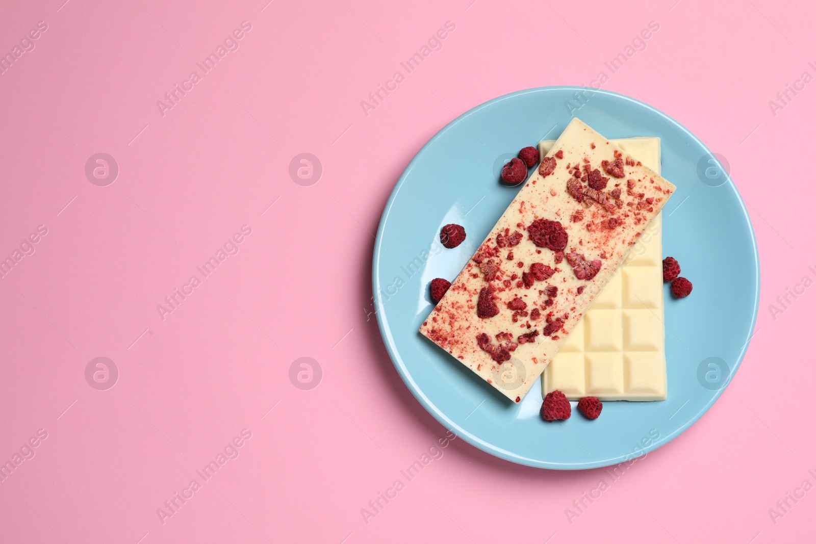 Photo of White chocolate with freeze dried fruits on pink background, top view. Space for text