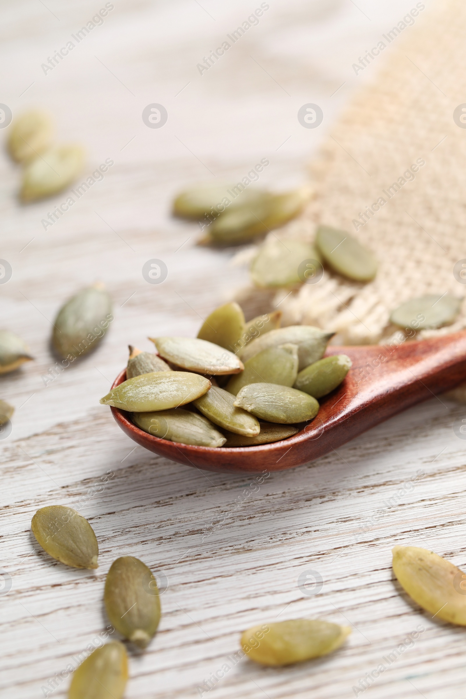 Photo of Spoon with peeled seeds on light wooden table