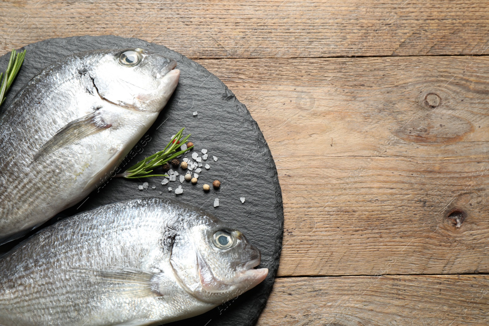 Photo of Raw dorada fish on wooden table, top view. Space for text