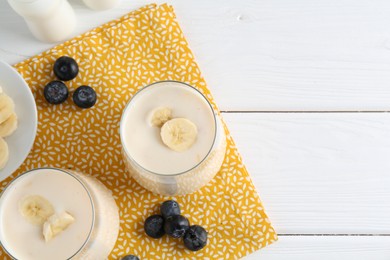 Tasty yogurt, banana and blueberries on white wooden table, top view. Space for text