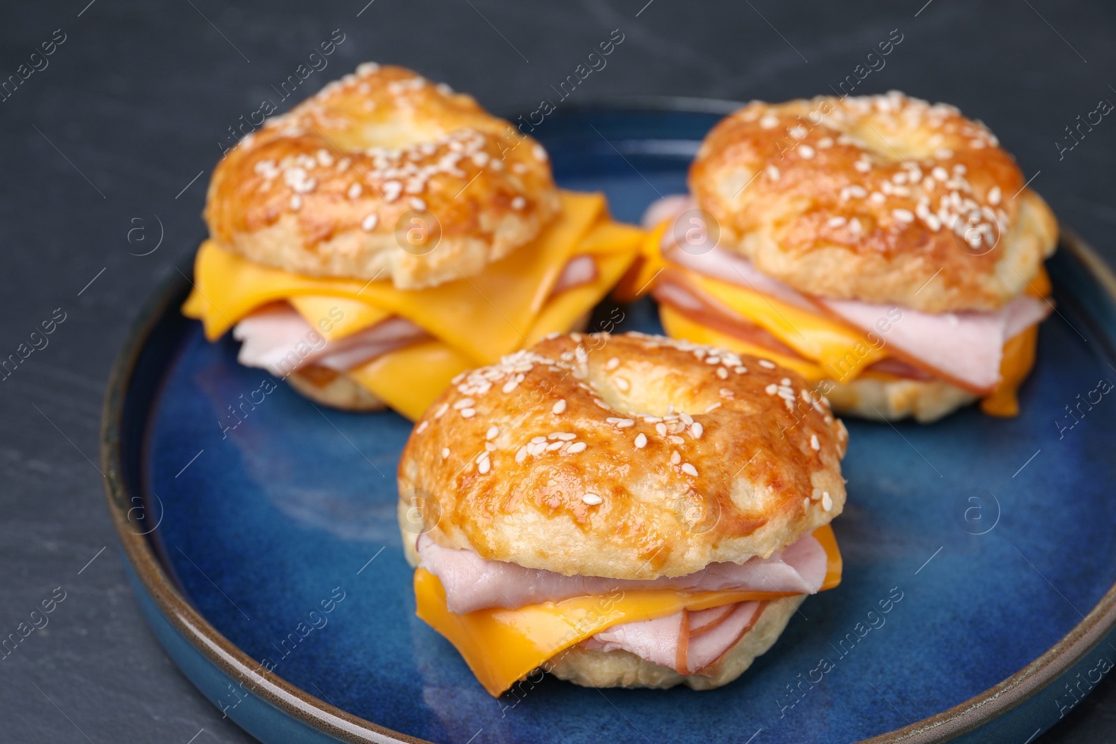 Delicious bagels with ham and cheese on black table, closeup Photo of Delicious bagels with ham and cheese on black table, closeup