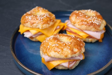 Photo of Delicious bagels with ham and cheese on black table, closeup