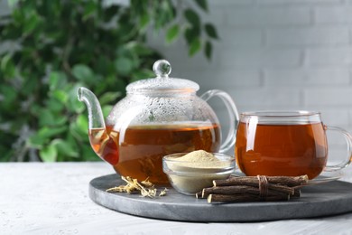 Photo of Aromatic licorice tea, dried sticks of licorice root and powder on light gray textured table