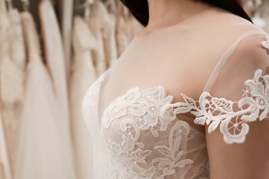 Photo of Woman trying on beautiful wedding dress in boutique, closeup