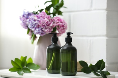 Soap dispensers and beautiful bouquet on table