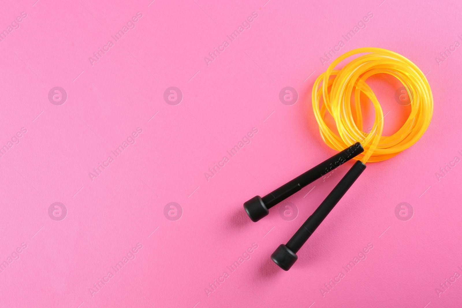 Photo of Skipping rope on pink background, top view. Space for text