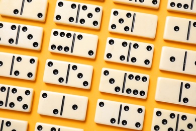 Photo of Classic domino tiles on yellow background, flat lay