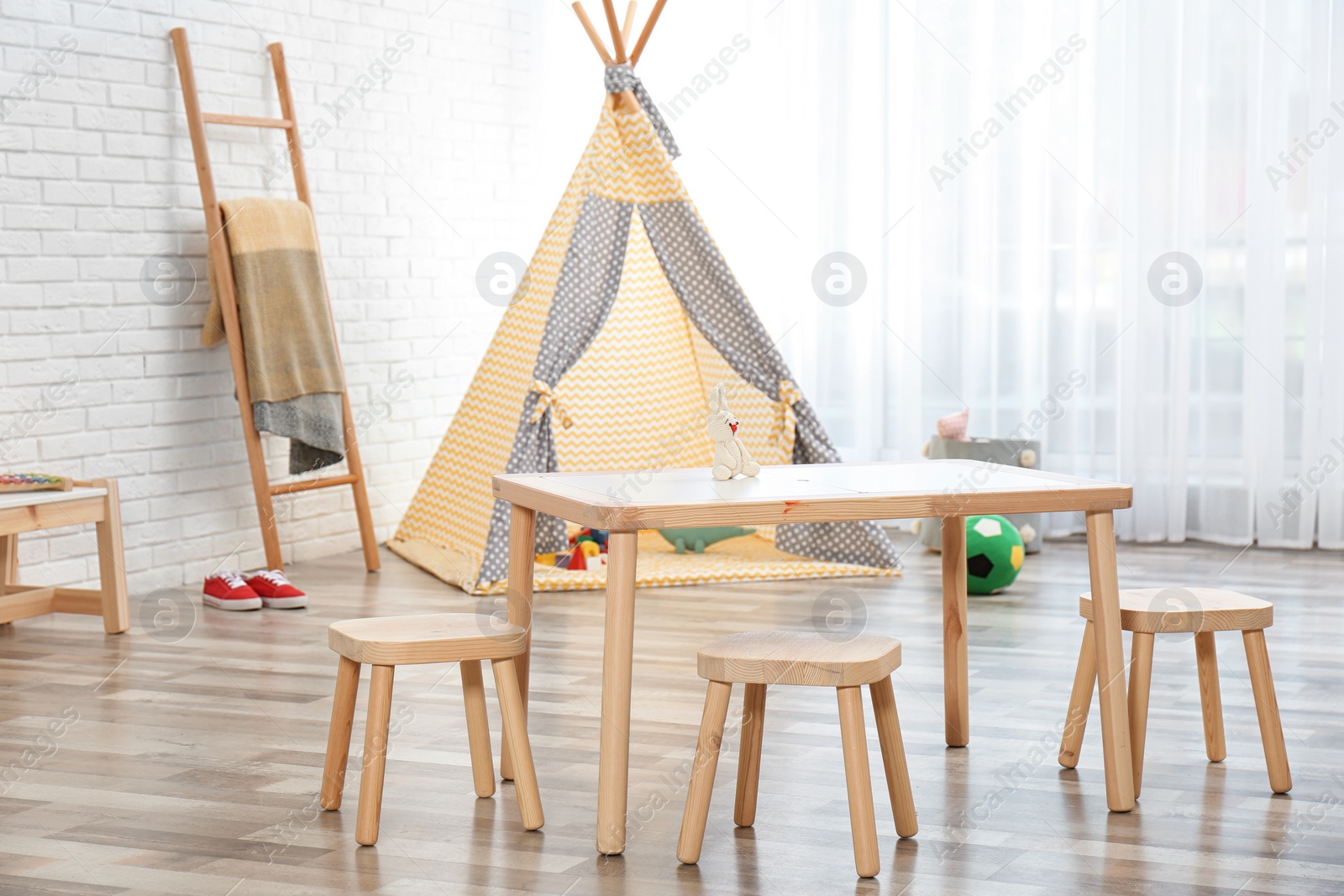 Photo of Cozy kids room interior with table, stools and play tent