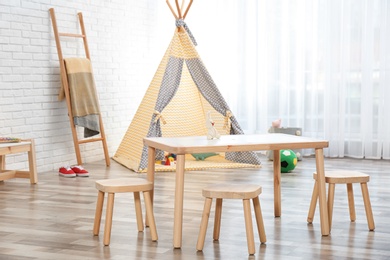 Cozy kids room interior with table, stools and play tent