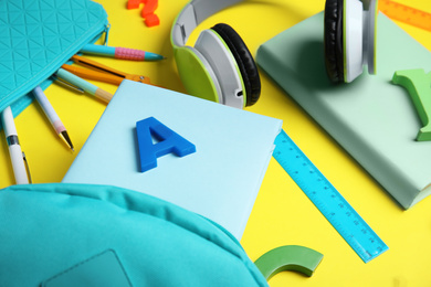 Photo of Books, headphones and school stationery on yellow background