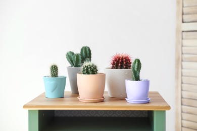 Photo of Beautiful different cacti in pots on table