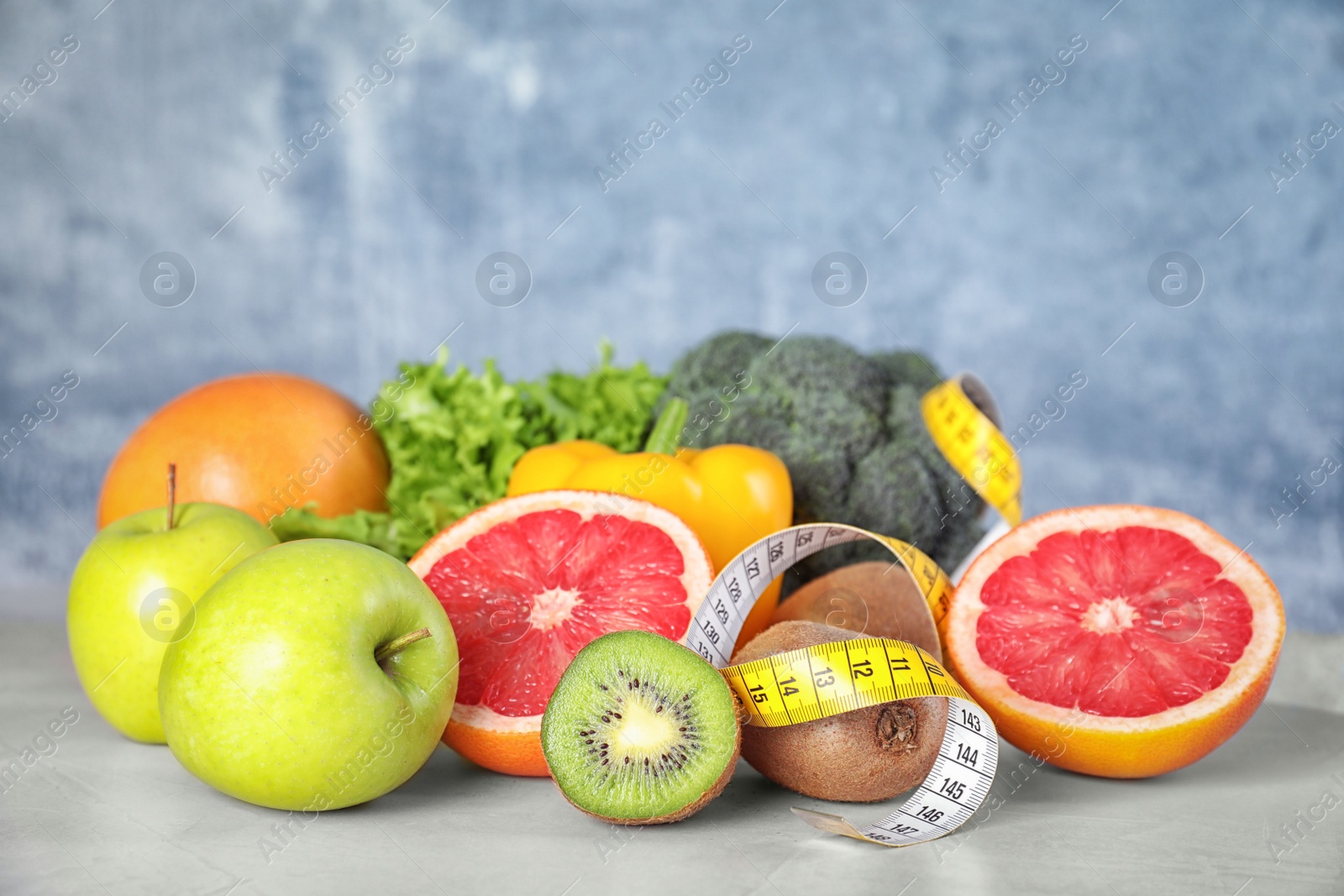 Photo of Measuring tape, vegetables and fruits on table. Diet plan from nutritionist