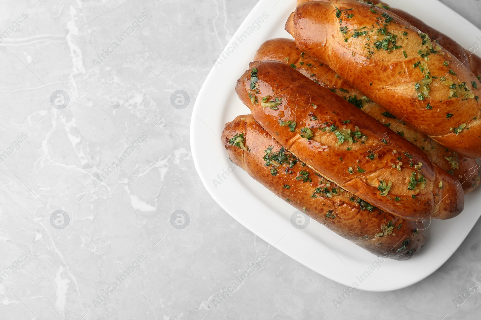 Photo of Plate of bread loaves with garlic and herbs on light table, top view. Space for text