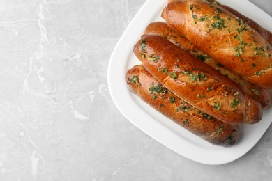 Plate of bread loaves with garlic and herbs on light table, top view. Space for text