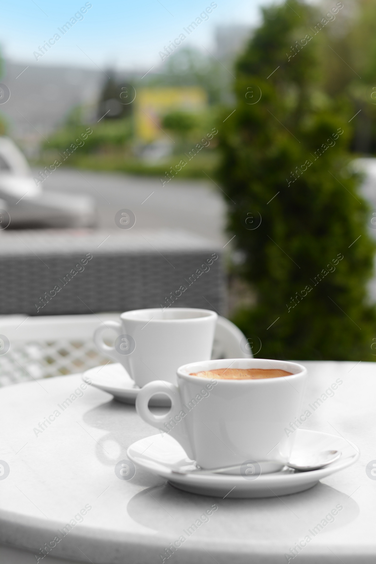 Photo of Ceramic cups of aromatic coffee with foam on table in morning