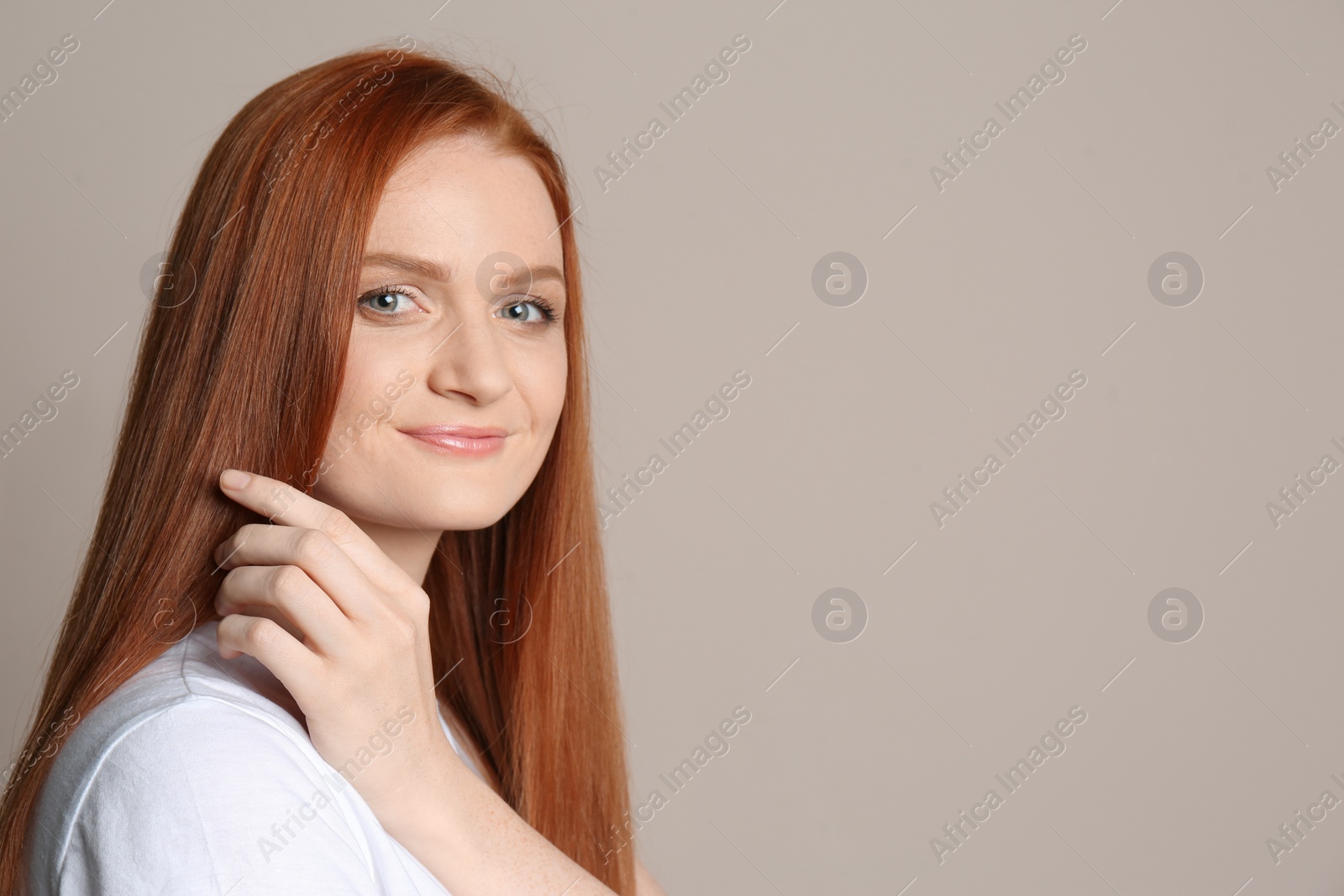 Photo of Candid portrait of happy young woman with charming smile and gorgeous red hair on beige background, space for text