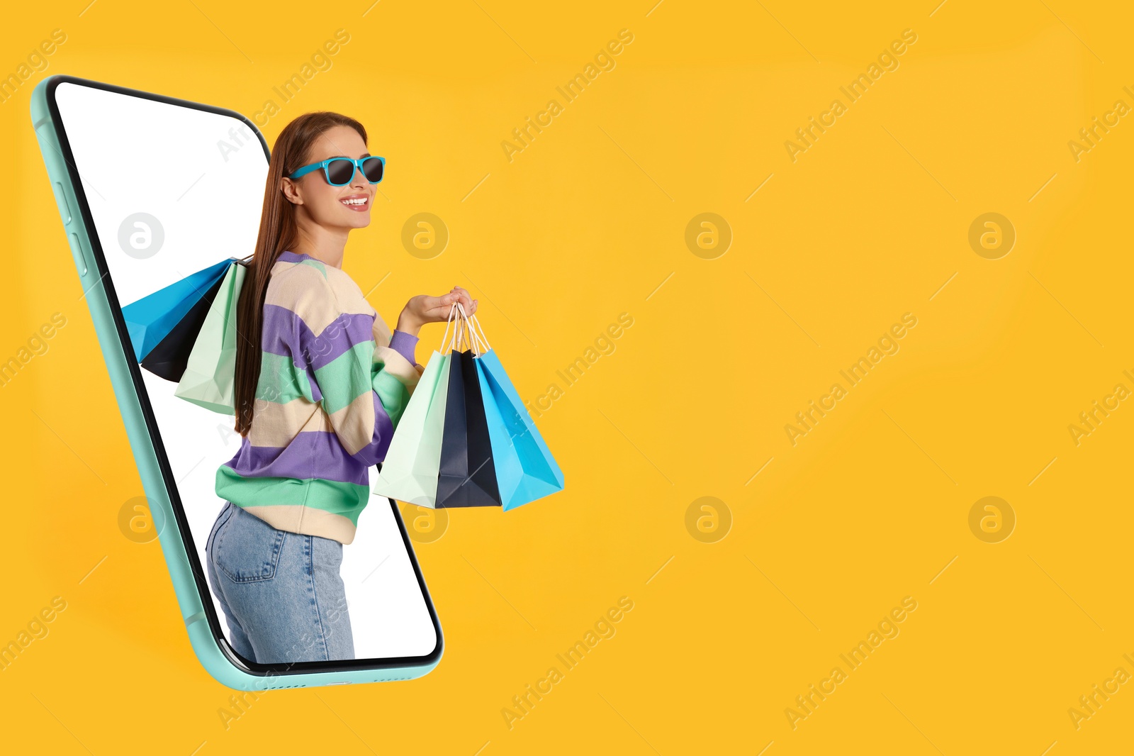 Image of Online shopping. Happy woman with paper bags looking out from smartphone on orange background, space for text