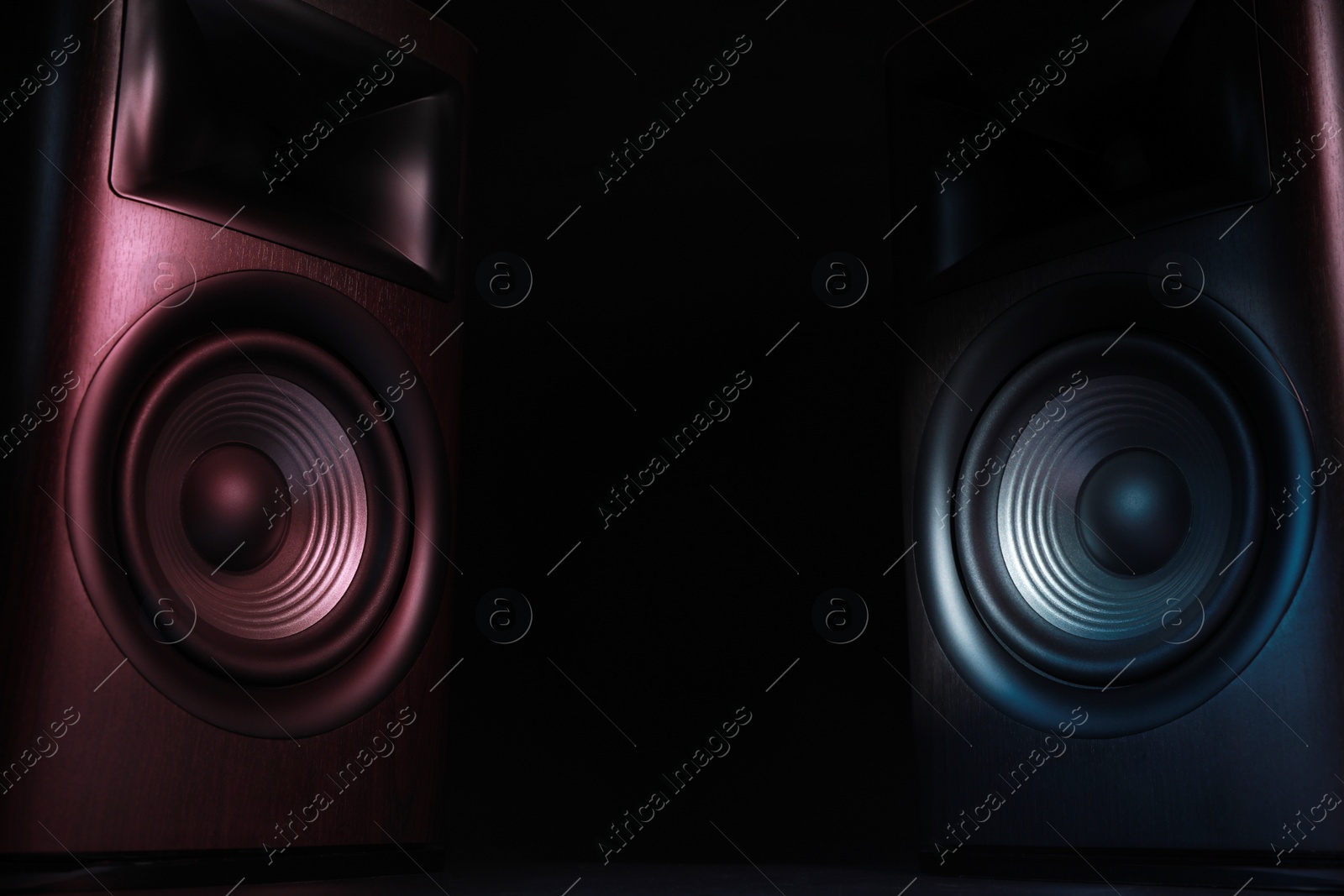 Photo of Modern sound speakers in neon light on black background. Space for text