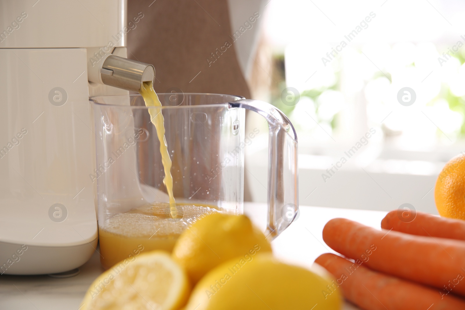 Photo of Modern juicer, fresh fruits and carrots on table in kitchen, closeup