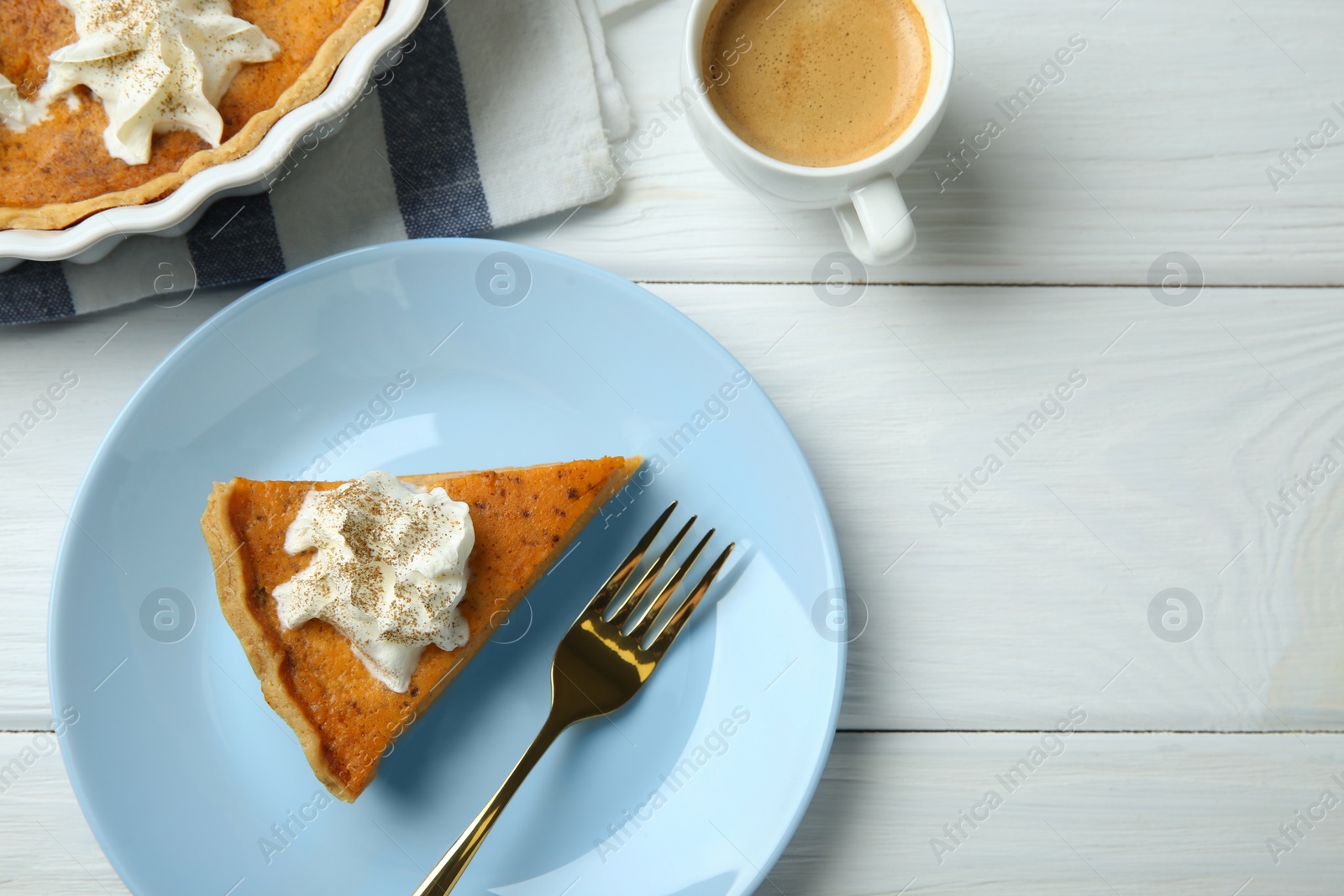 Photo of Delicious pumpkin pie with whipped cream, fork and cup of coffee on white wooden table, flat lay. Space for text