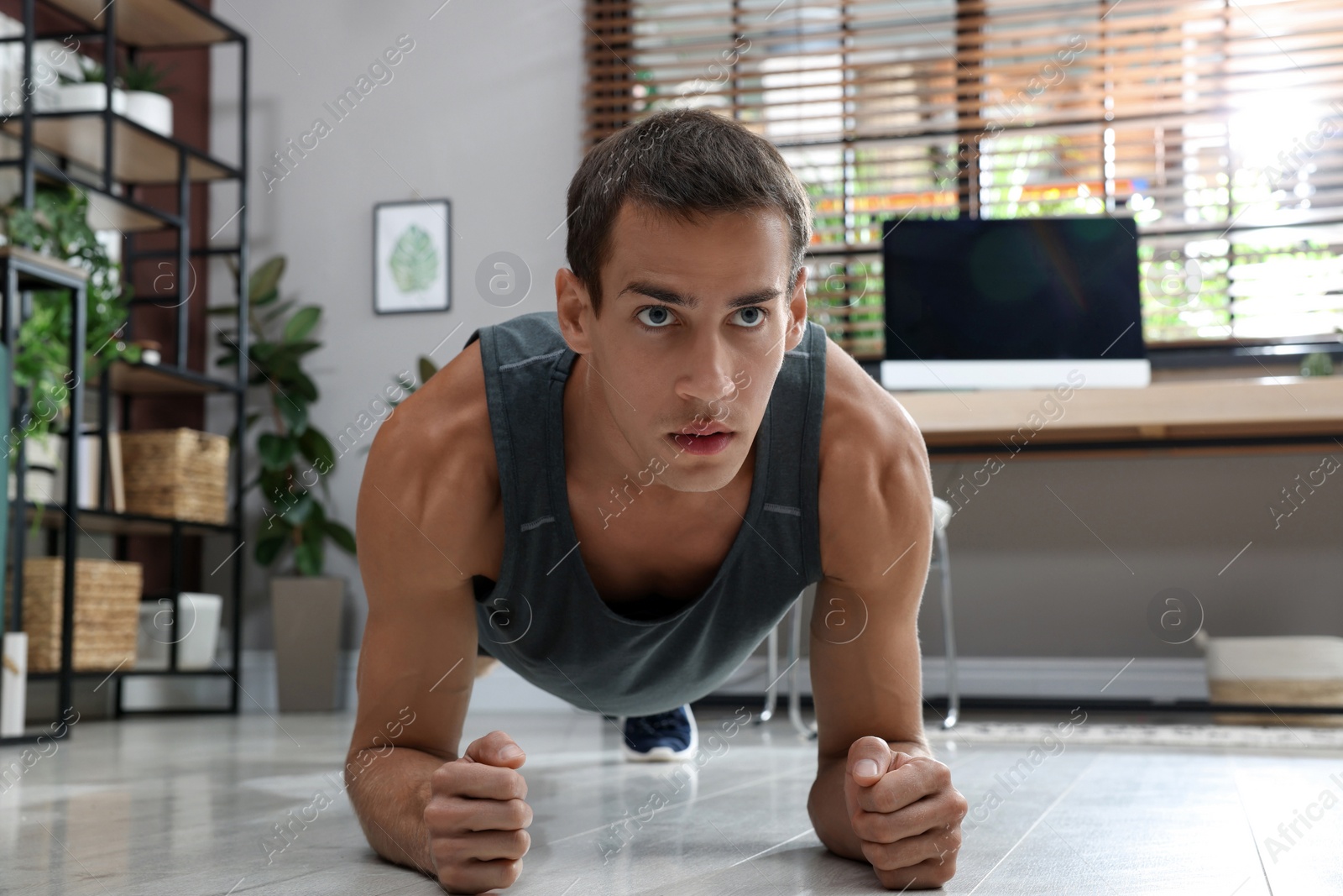 Photo of Handsome man doing plank exercise on floor at home