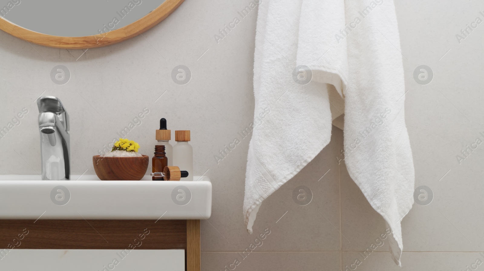 Photo of Hanging towel, sink and toiletries in bathroom. Interior design