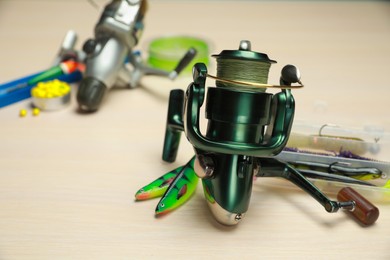 Photo of Reels with fishing line and other equipment on light wooden table, closeup. Space for text