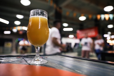 Glass of beer on wooden table in pub