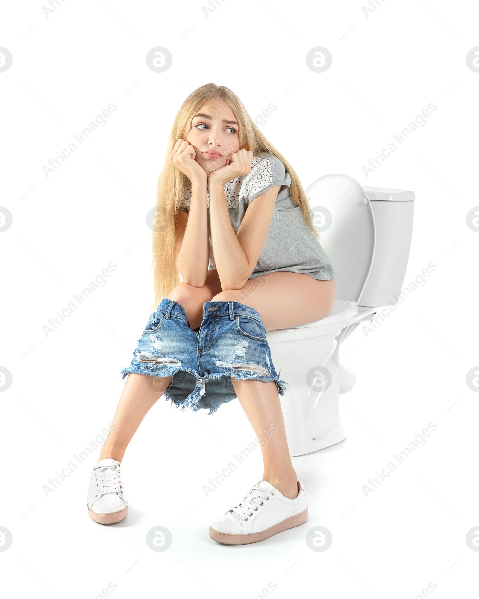 Photo of Young woman sitting on toilet bowl. Isolated on white