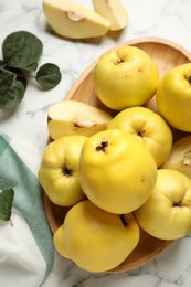 Photo of Fresh ripe organic quinces with leaves on white marble table, flat lay