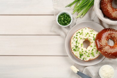 Photo of Delicious bagel with cream cheese and green onion on white wooden table, flat lay. Space for text