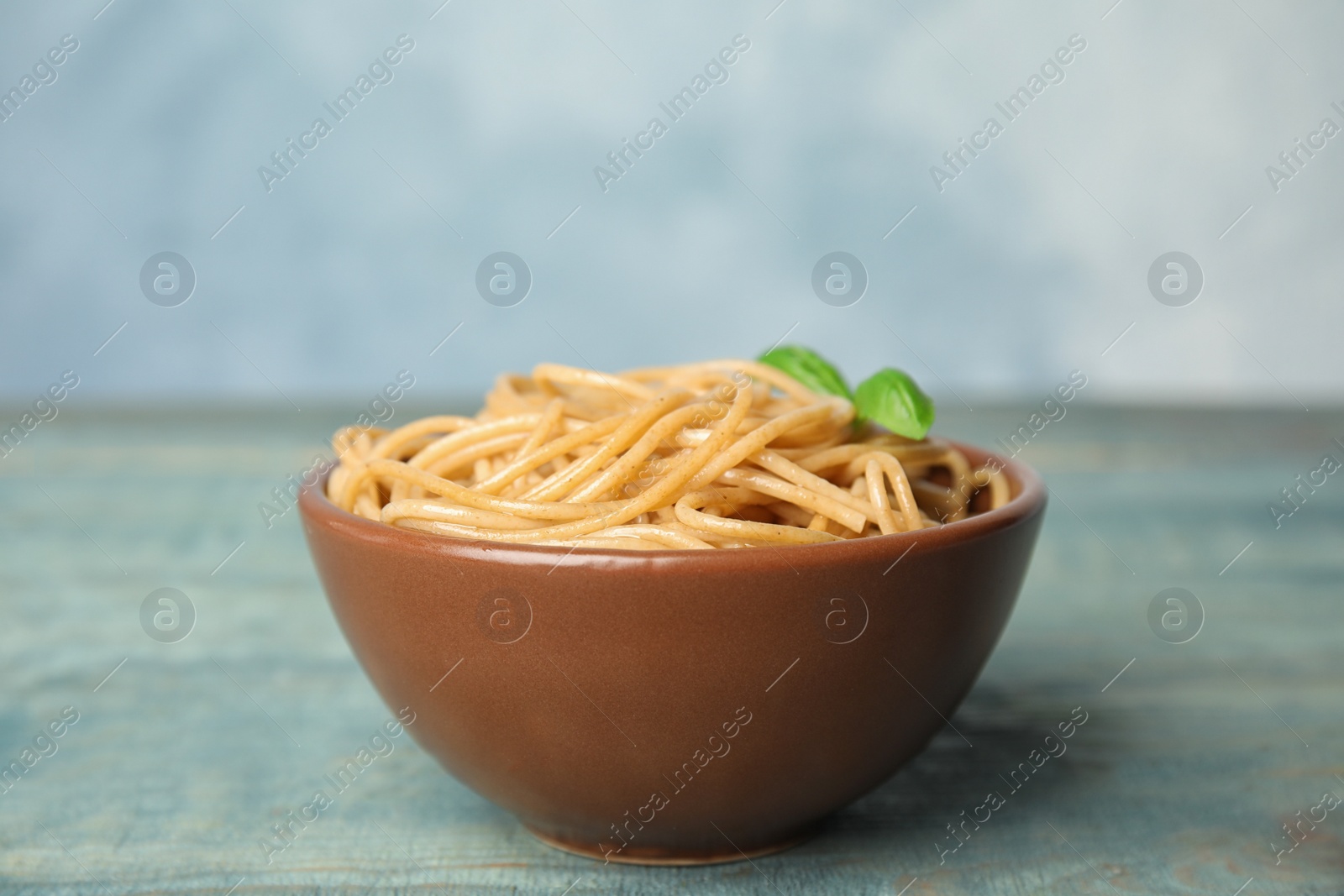 Photo of Tasty buckwheat noodles in bowl on blue wooden table