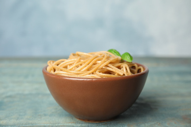 Photo of Tasty buckwheat noodles in bowl on blue wooden table