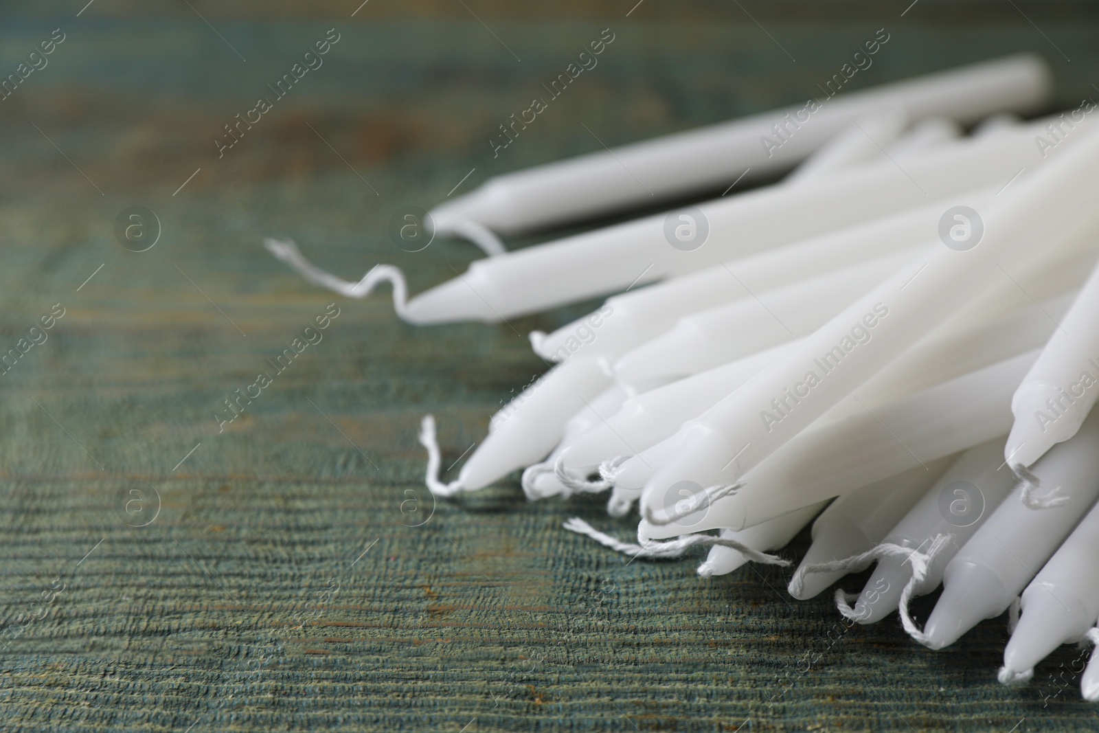 Photo of Many church wax candles on old wooden table, closeup. Space for text