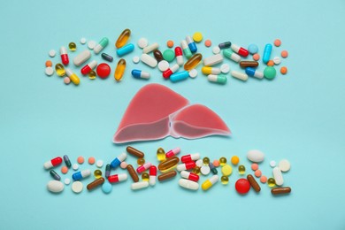 Paper liver and pills on turquoise background, flat lay. Hepatitis treatment