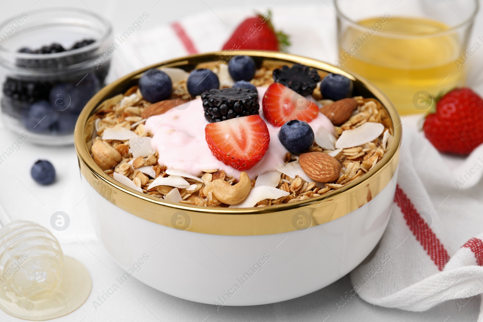 Photo of Tasty granola, yogurt and fresh berries in bowl on white table, closeup. Healthy breakfast